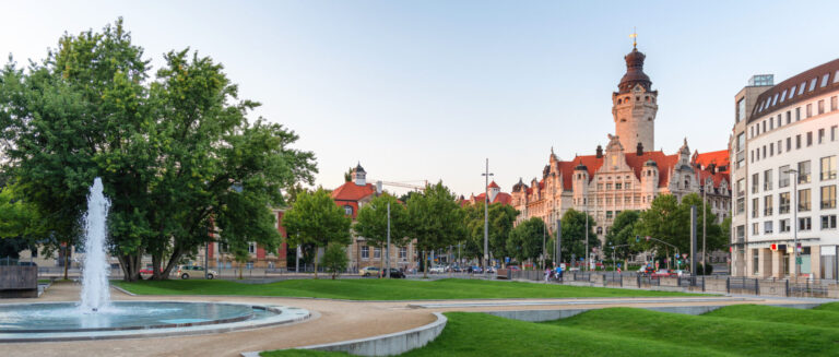 Blick auf das Neue Rathaus in Leipzig am Wilhelm-Leuschner-Platz mit Springbrunnen, Grünanlage und historischer Architektur in der Leipziger Innenstadt.